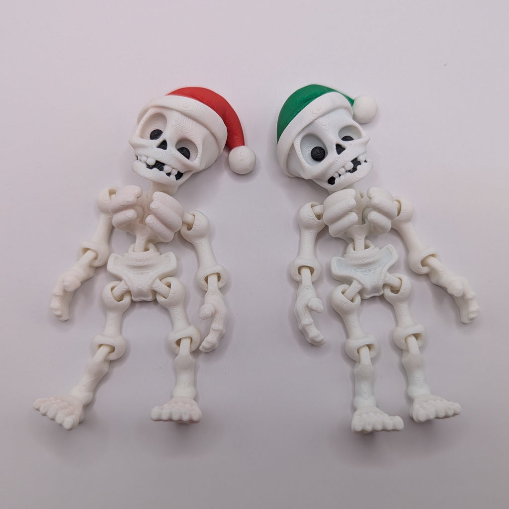 Two small skeleton figures wearing Santa hats on a light gray background